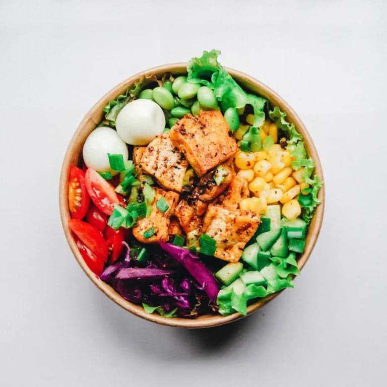 A colourful bowl of grilled protein, greens and fresh vegetables